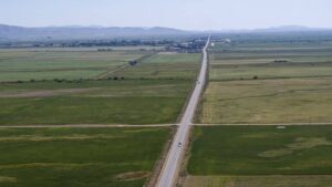 2169119577_Highway cuts through Idaho vast farmlands towards distant mountains._Large-cm