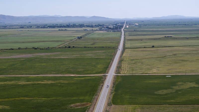 2169119577_Highway cuts through Idaho vast farmlands towards distant mountains._Large-cm